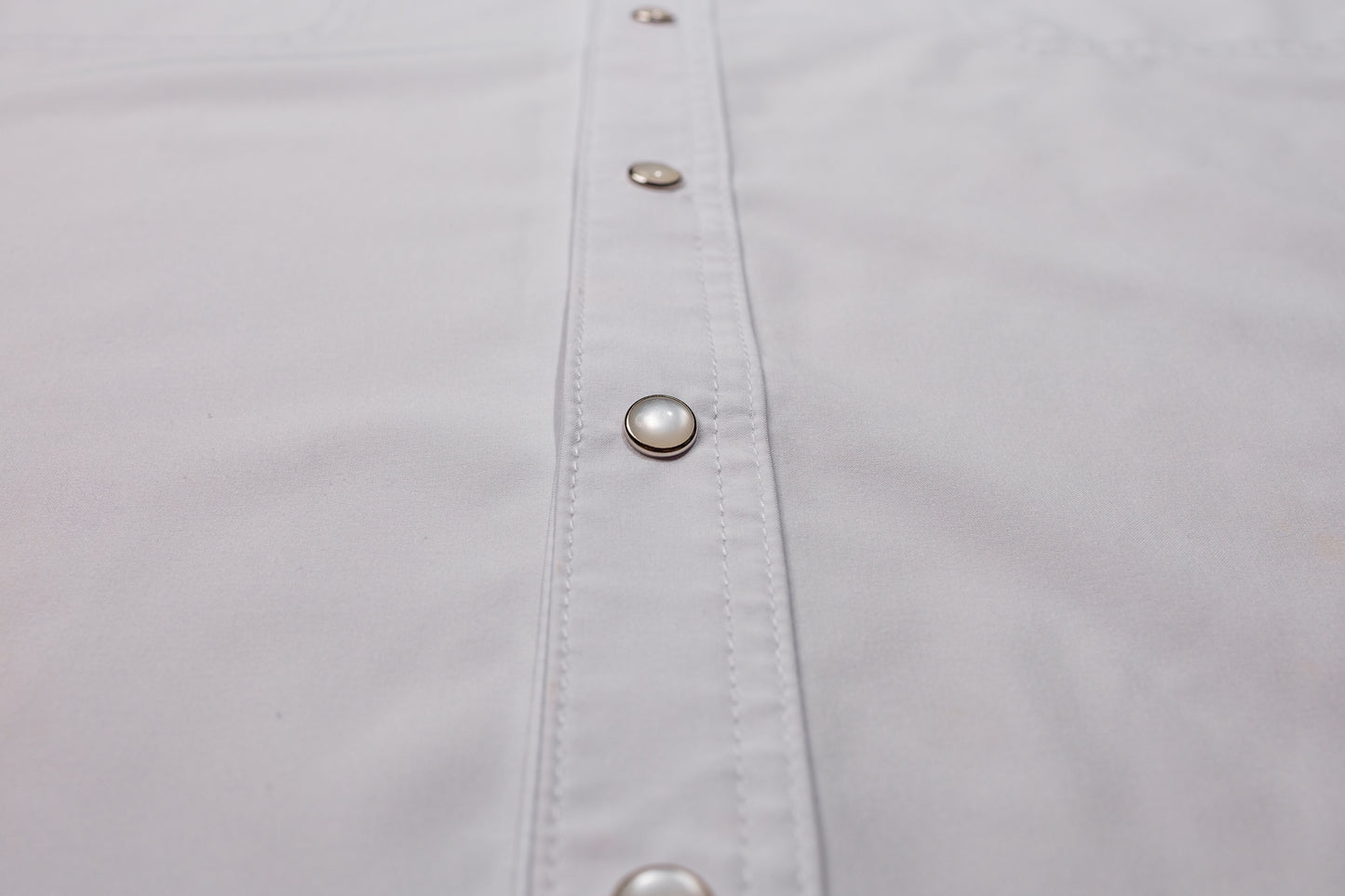 Close-up of a white shirt with pearl snaps on placket