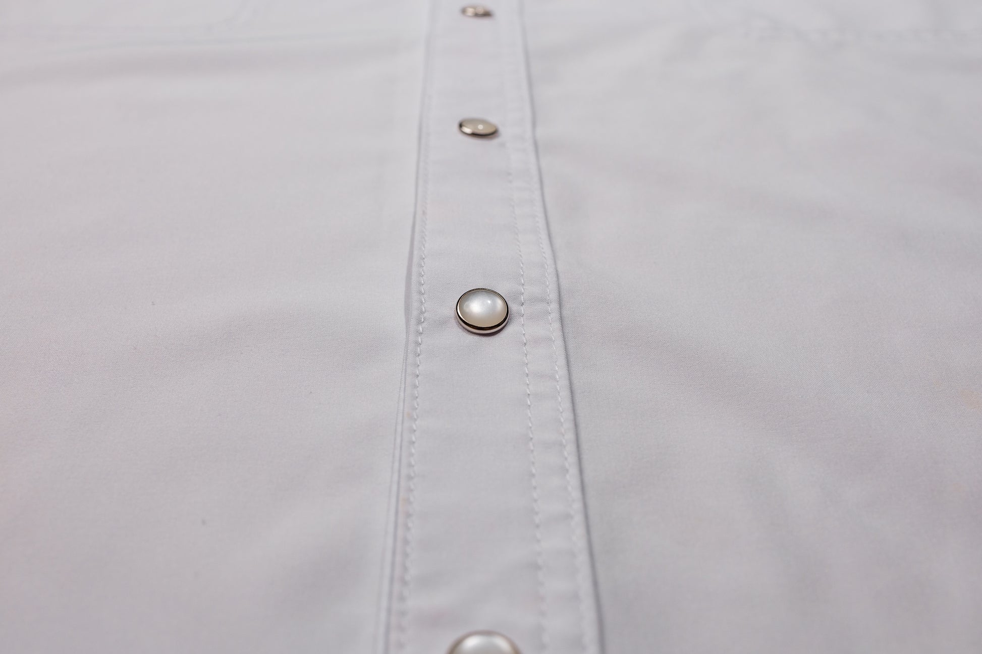Close-up of a white shirt with pearl snaps on placket